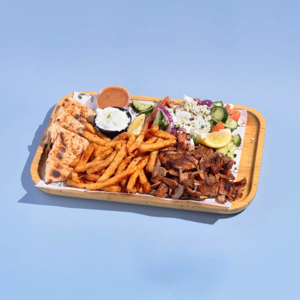 Efi's Gyro platter with grilled meat, fries, pita bread, Greek salad, and dipping sauces.