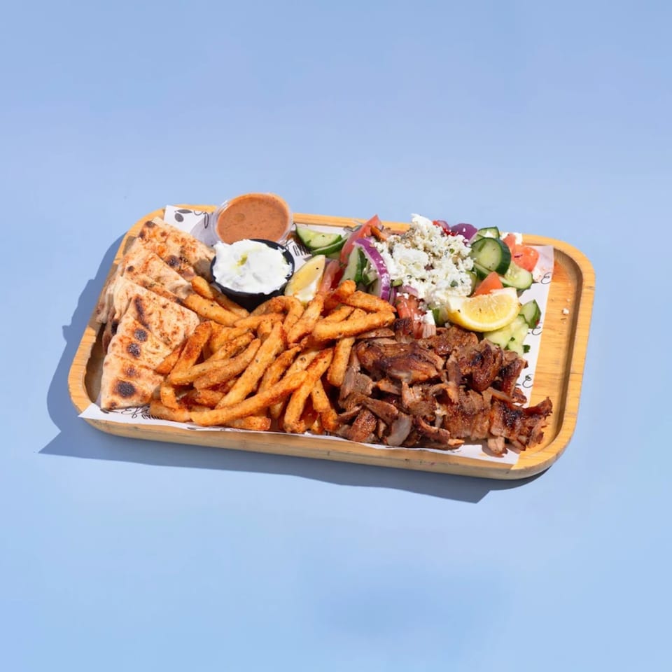 Efi's Gyro platter with grilled meat, fries, pita bread, Greek salad, and dipping sauces.