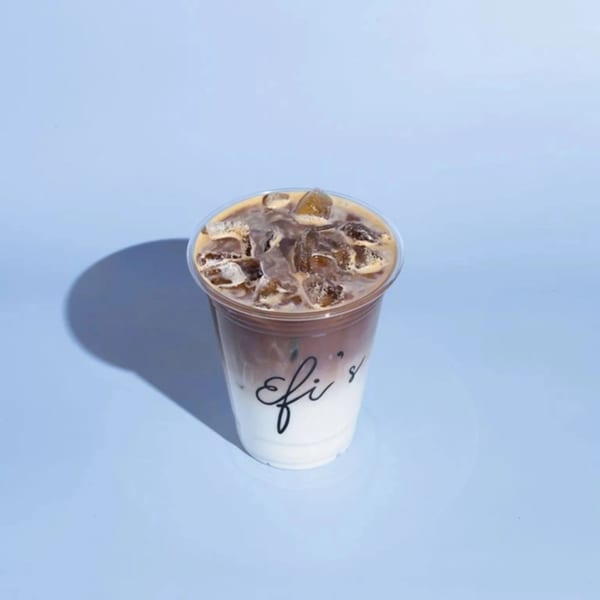 Iced coffee with milk and ice in a clear plastic cup with "Efi's" logo.