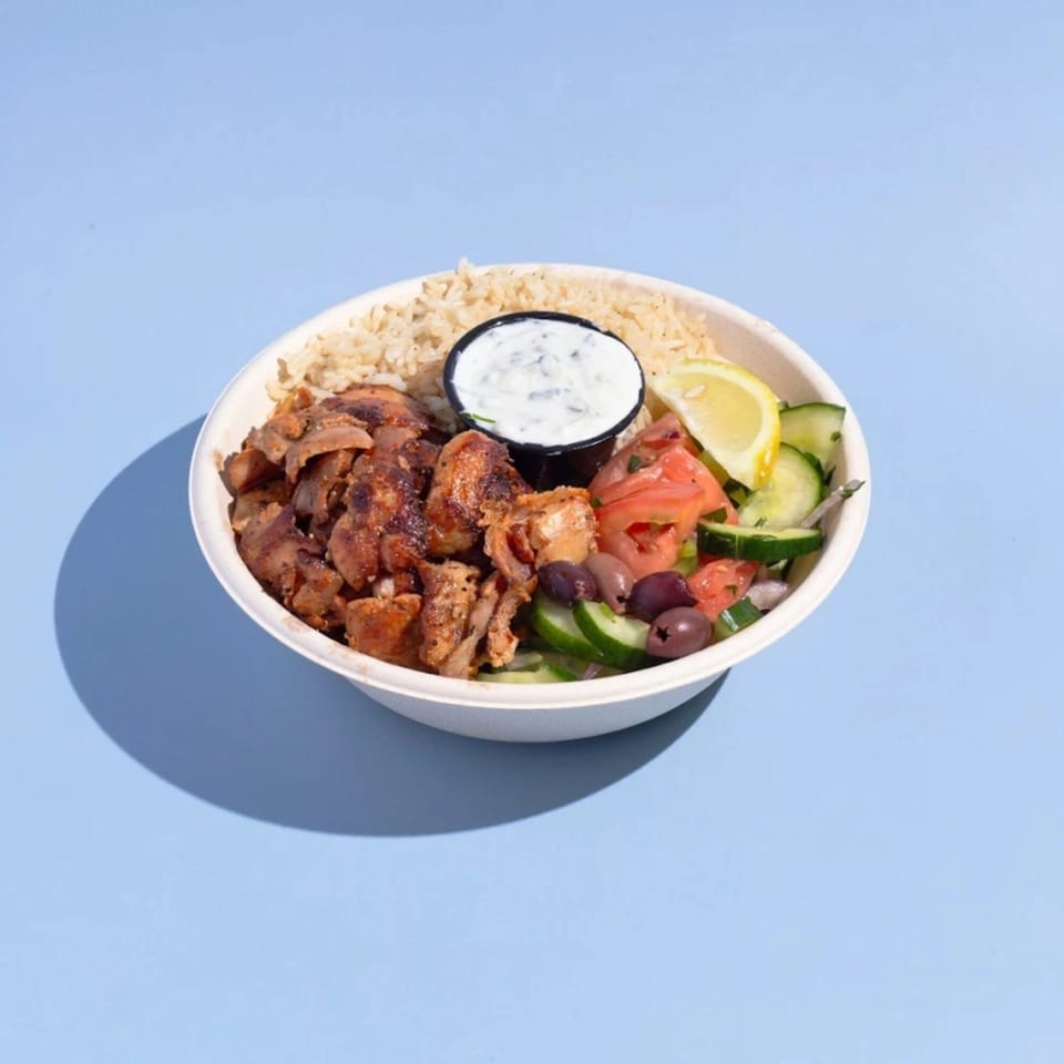 Efi's Gyro bowl with rice, gyro meat, tzatziki, Greek salad, and a lemon wedge.